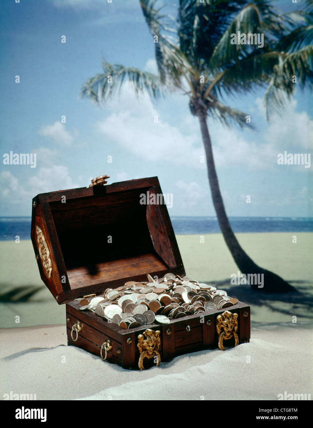 1960s PIRATE TREASURE CHEST FULL COINS ON TROPICAL BEACH Stock Photo