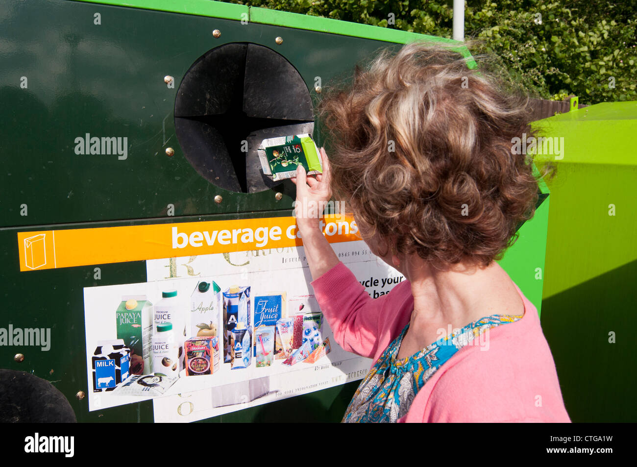Woman putting juice cartons into collection container at recycling