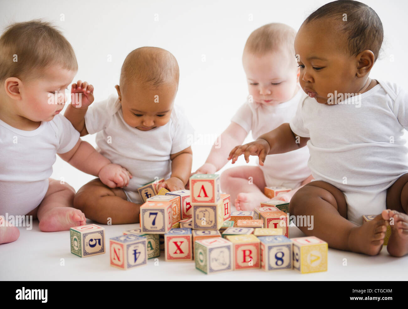 Babies sitting on floor playing with blocks Stock Photo