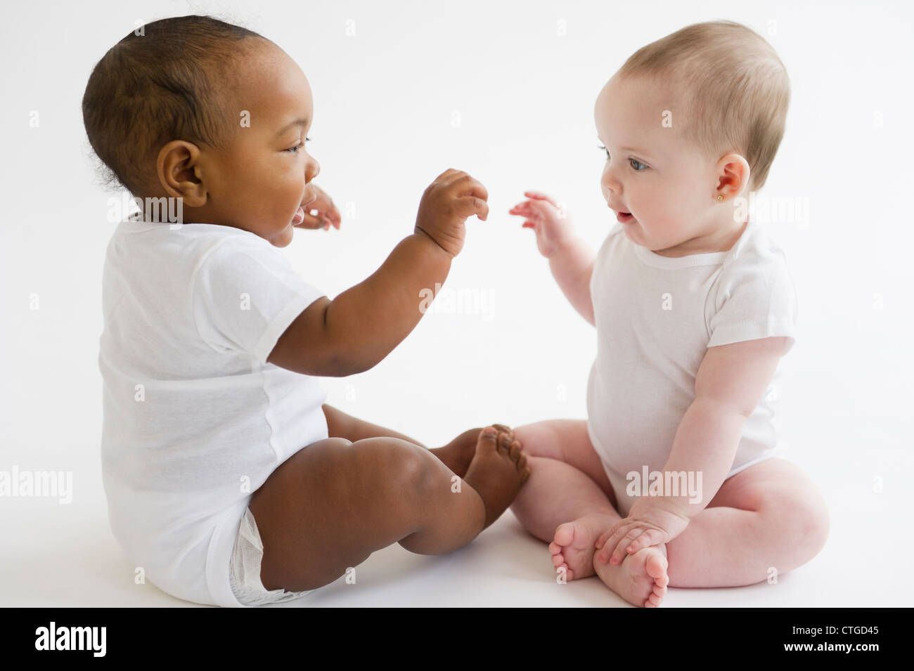 Babies playing together on floor Stock Photo