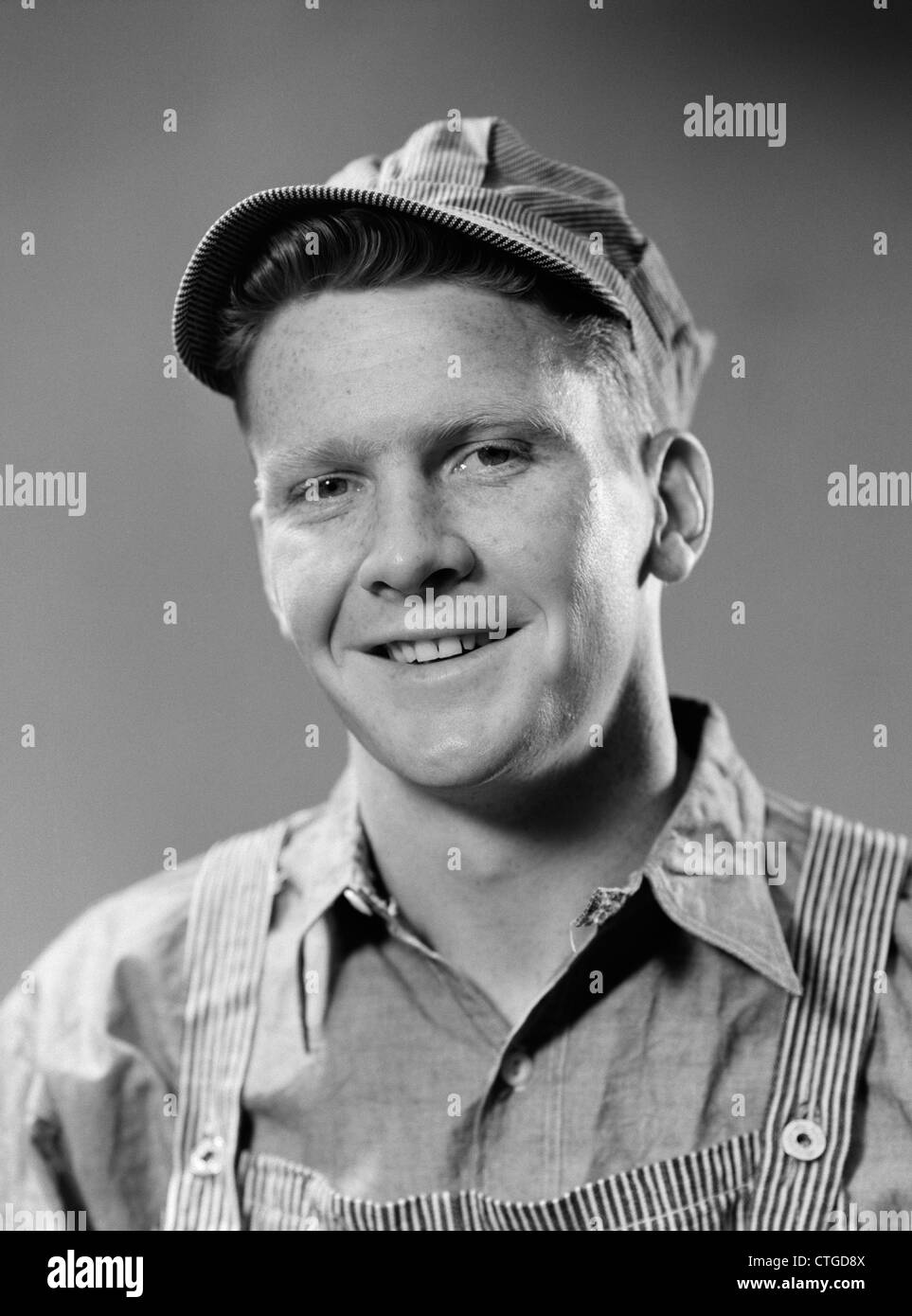 1940s PORTRAIT OF SMILING BLUE COLLAR WORKING MAN WEARING OVERALLS