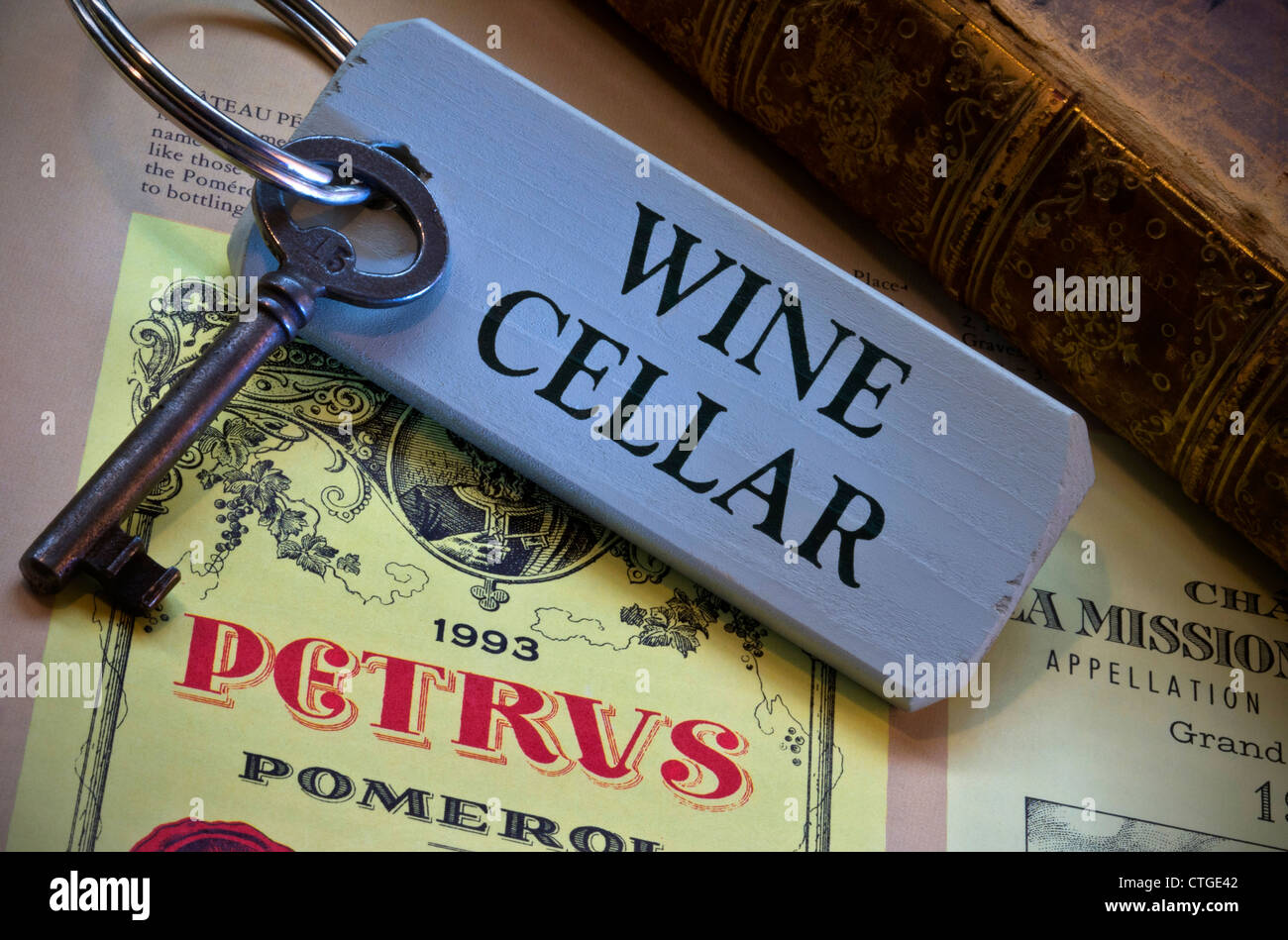 Wine cellar key by old leather bound book and an illustration of a  Petrus fine Pomerol wine bottle label in reference book Stock Photo
