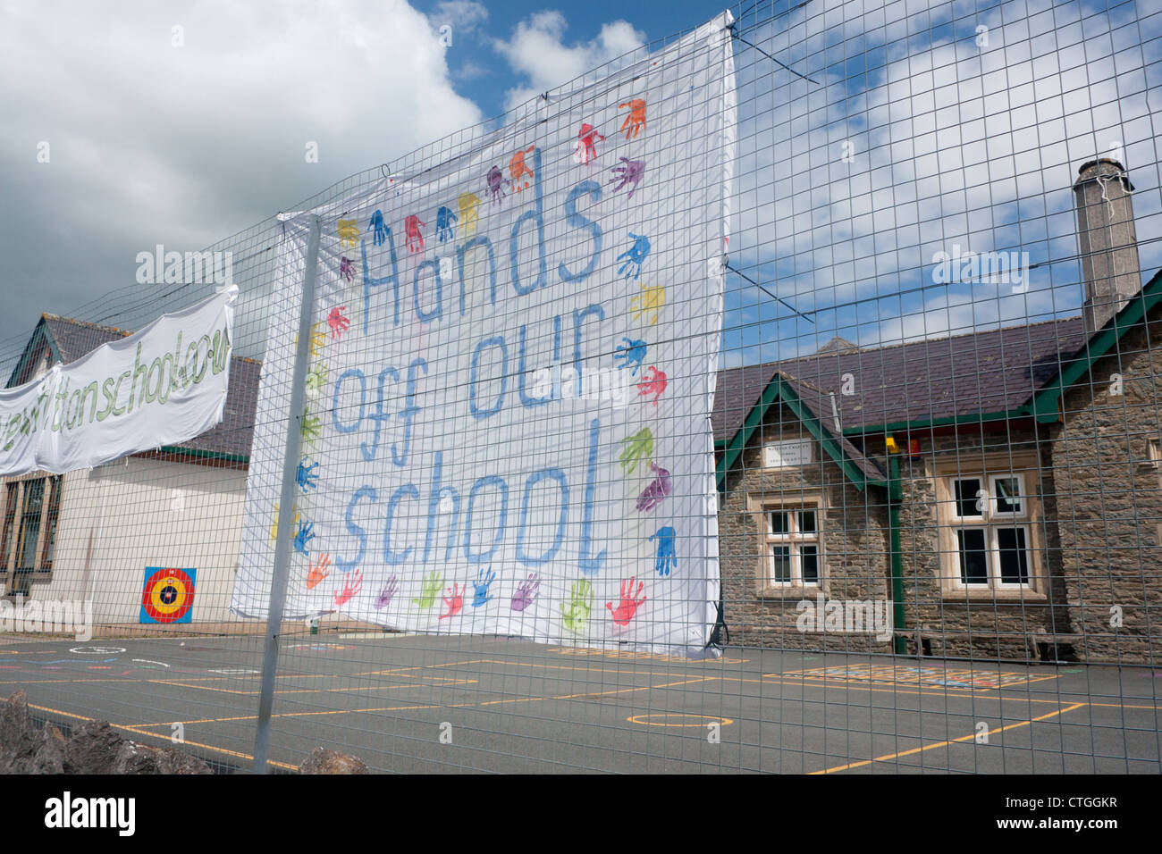 'Hands off our school' hand-painted sign / banner with children's handprints outside Whitton Primary School Powys Mid Wales UK Stock Photo