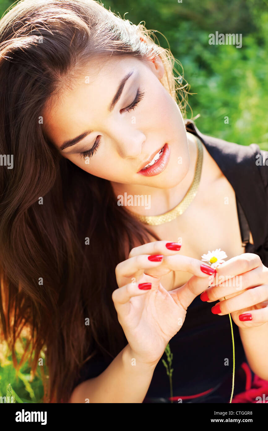 Pretty woman in park holding spring flowers, outdoor Stock Photo