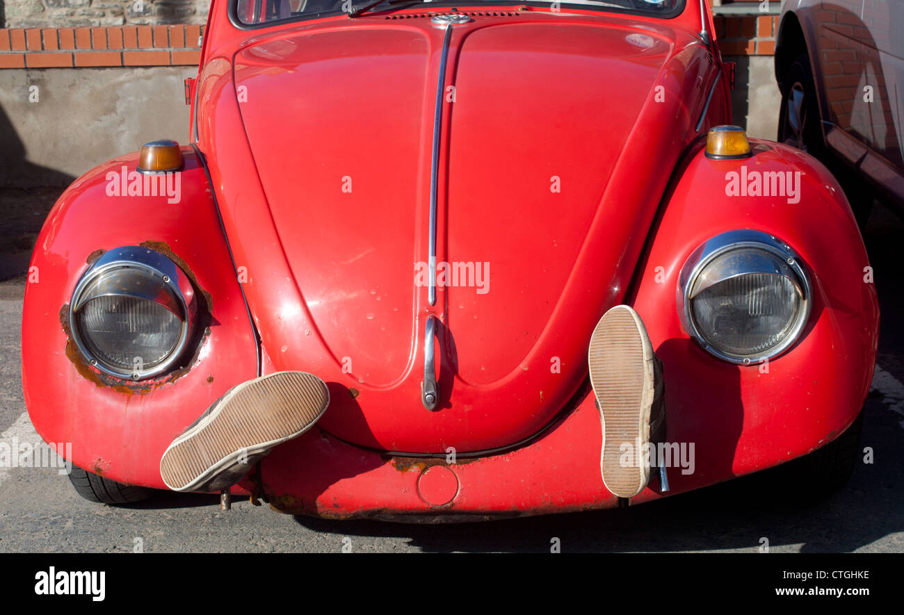 Front view of classic old red painted Volkswagen Beetle car with pair of shoes on front next to headlights Ceredigion Wales UK Stock Photo