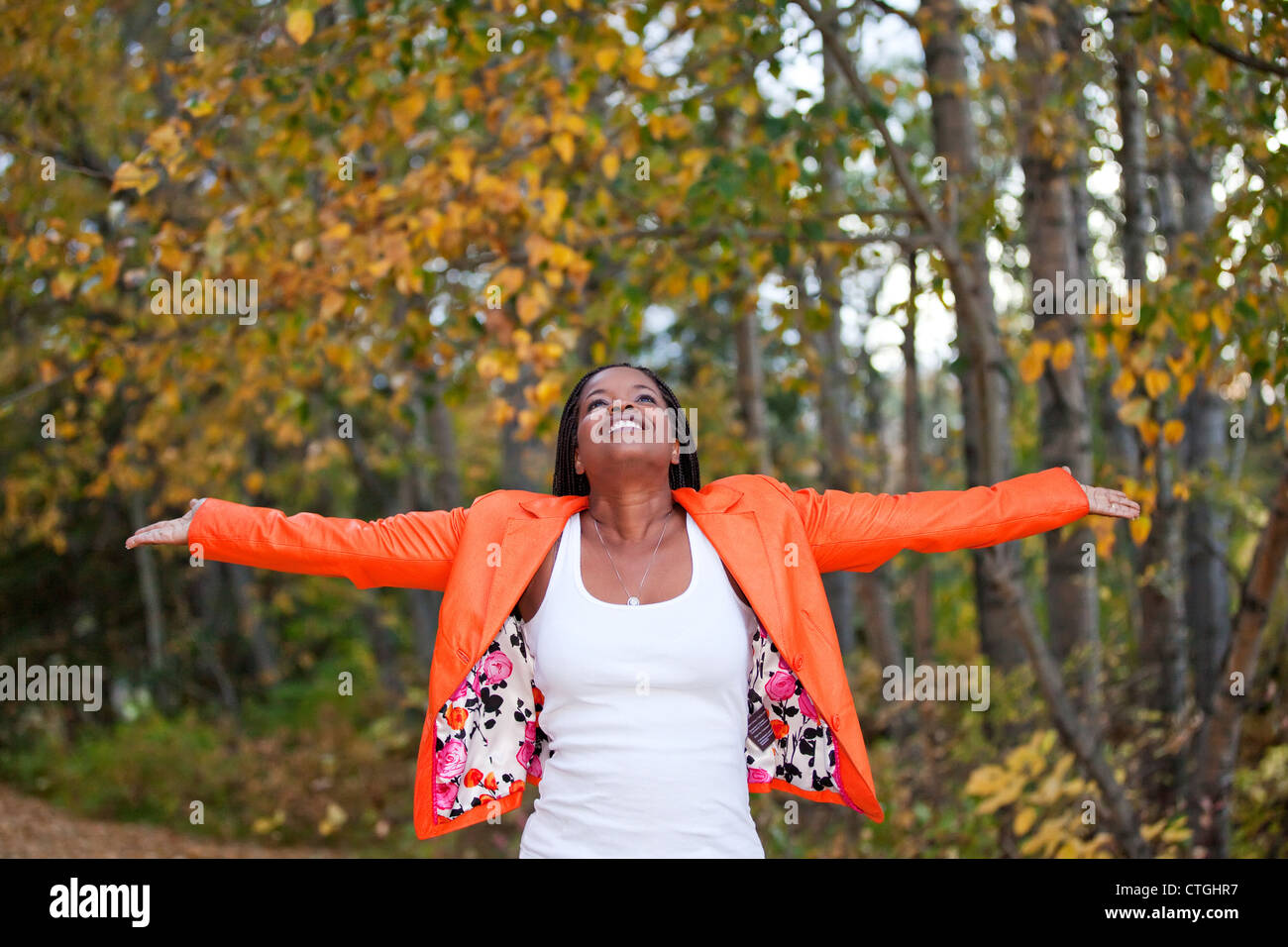 Woman Spreading Arms And Looking Upwards In A Park In Autumn; Edmonton, Alberta, Canada Stock Photo