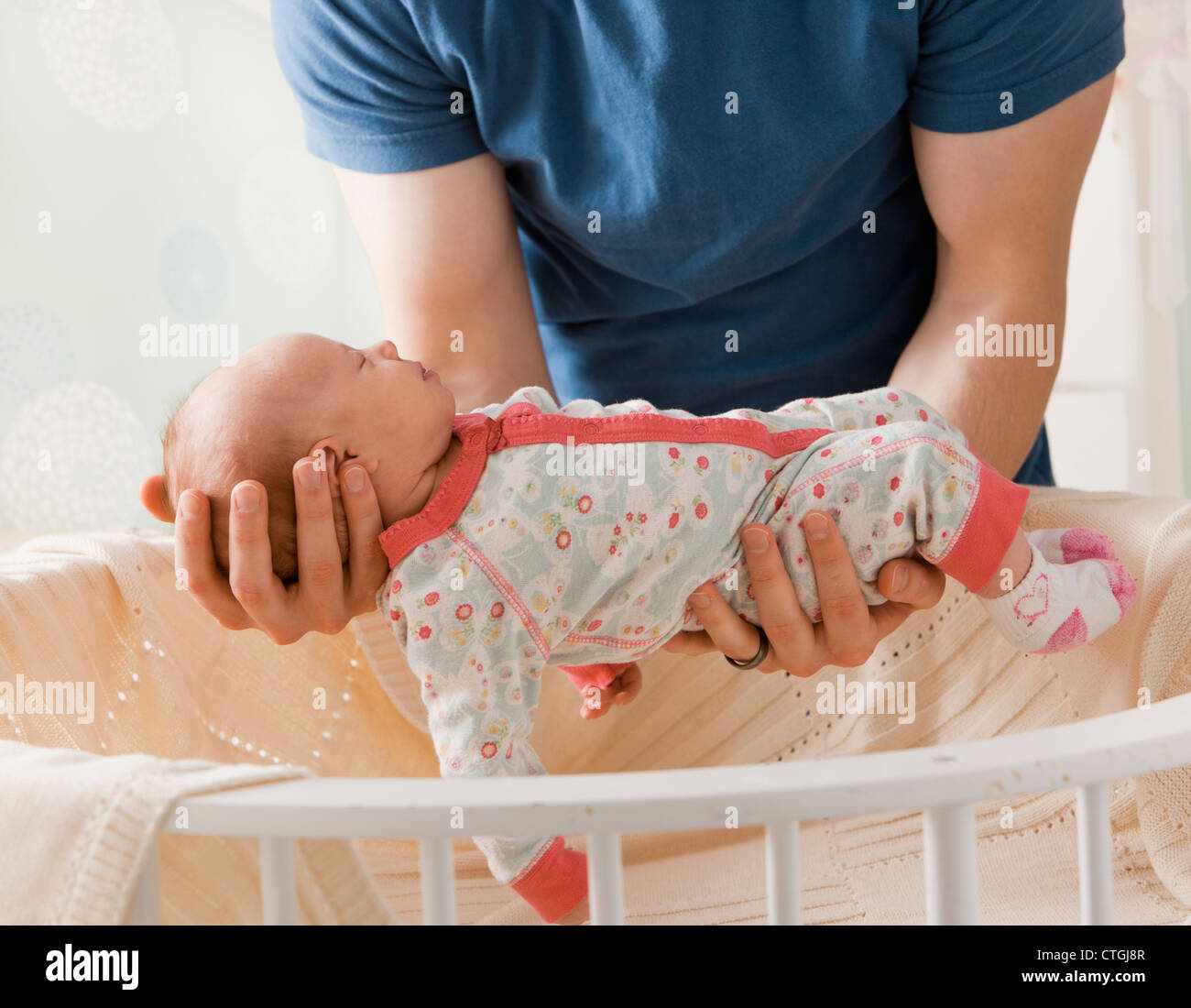 Caucasian father lifting baby girl from crib Stock Photo
