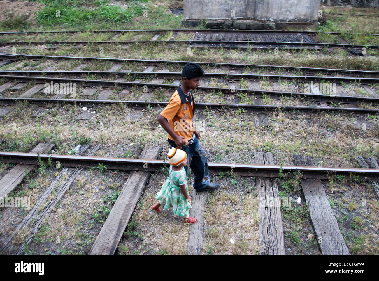 a boy and young girl walk along train, rail tracks in sri lanka Stock Photo