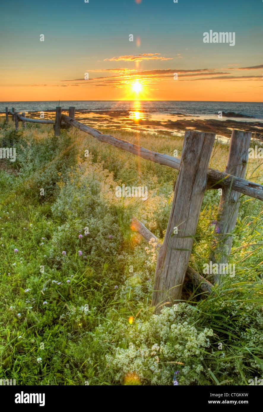 Sunset Over Water And A Fence Along The Shoreline; La Martre, Quebec ...