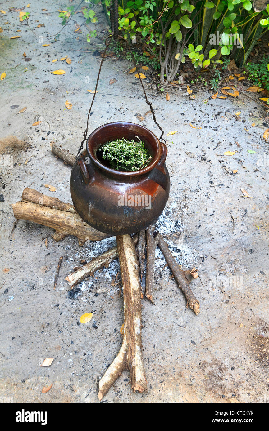 Herbs simmer in a clay pot over a small fire. Riviera Maya, Yucatan, Mexico. The herbs are used in spa therapy treatments. Stock Photo