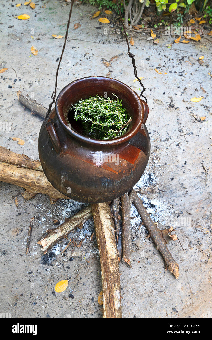 Herbs simmer in a clay pot over a small fire. Riviera Maya, Yucatan, Mexico. The herbs are used in spa therapy treatments. Stock Photo