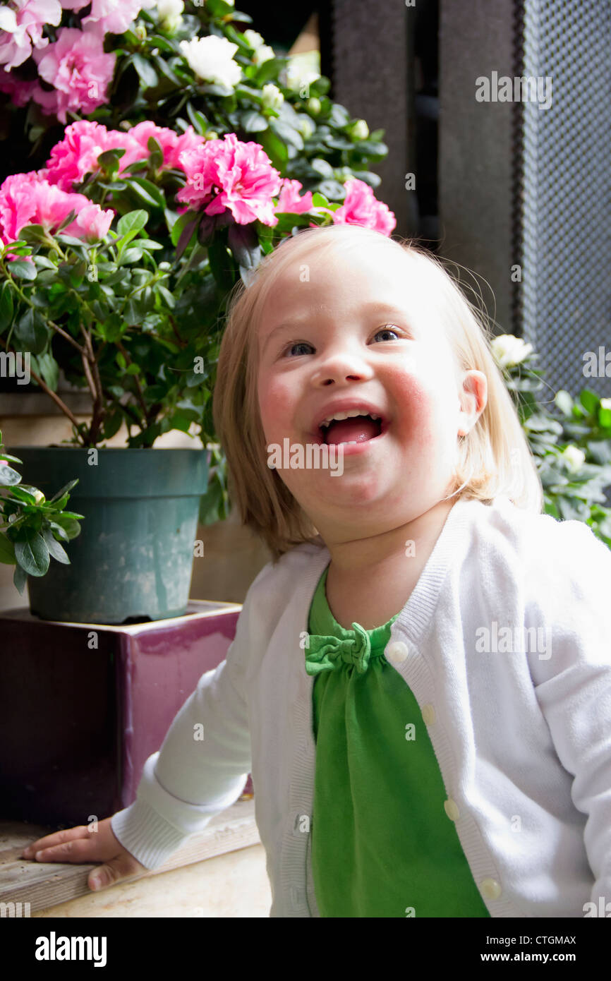 Portrait Of A Young Girl With Down Syndrome Beside Flower Pots; Vancouver, British Columbia, Canada Stock Photo