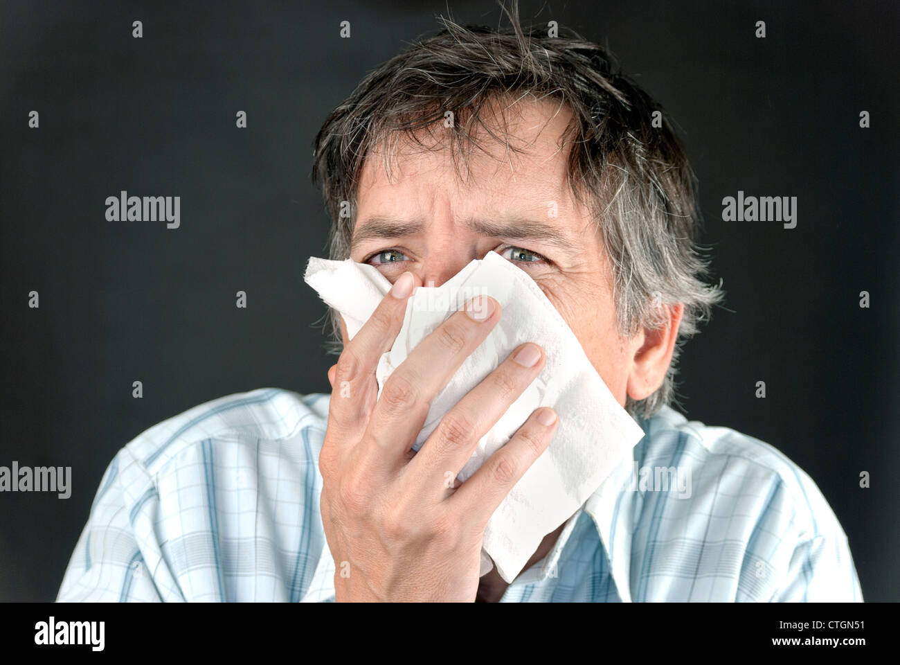 Close-up of a man sneezing into a tissue. Stock Photo