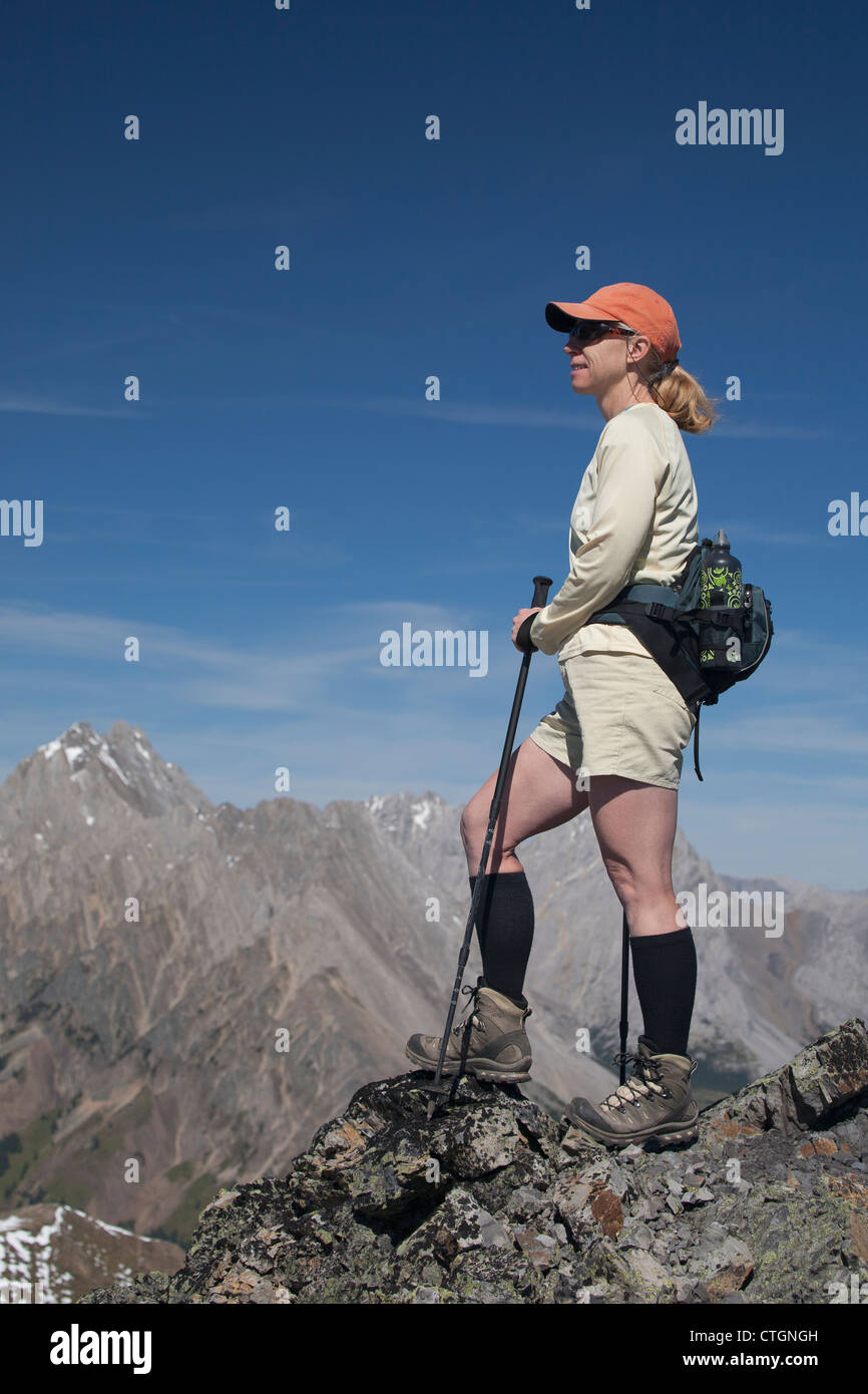 Female Hiker Standing On Rock Cliff Overlooking Mountains And Blue Sky ...