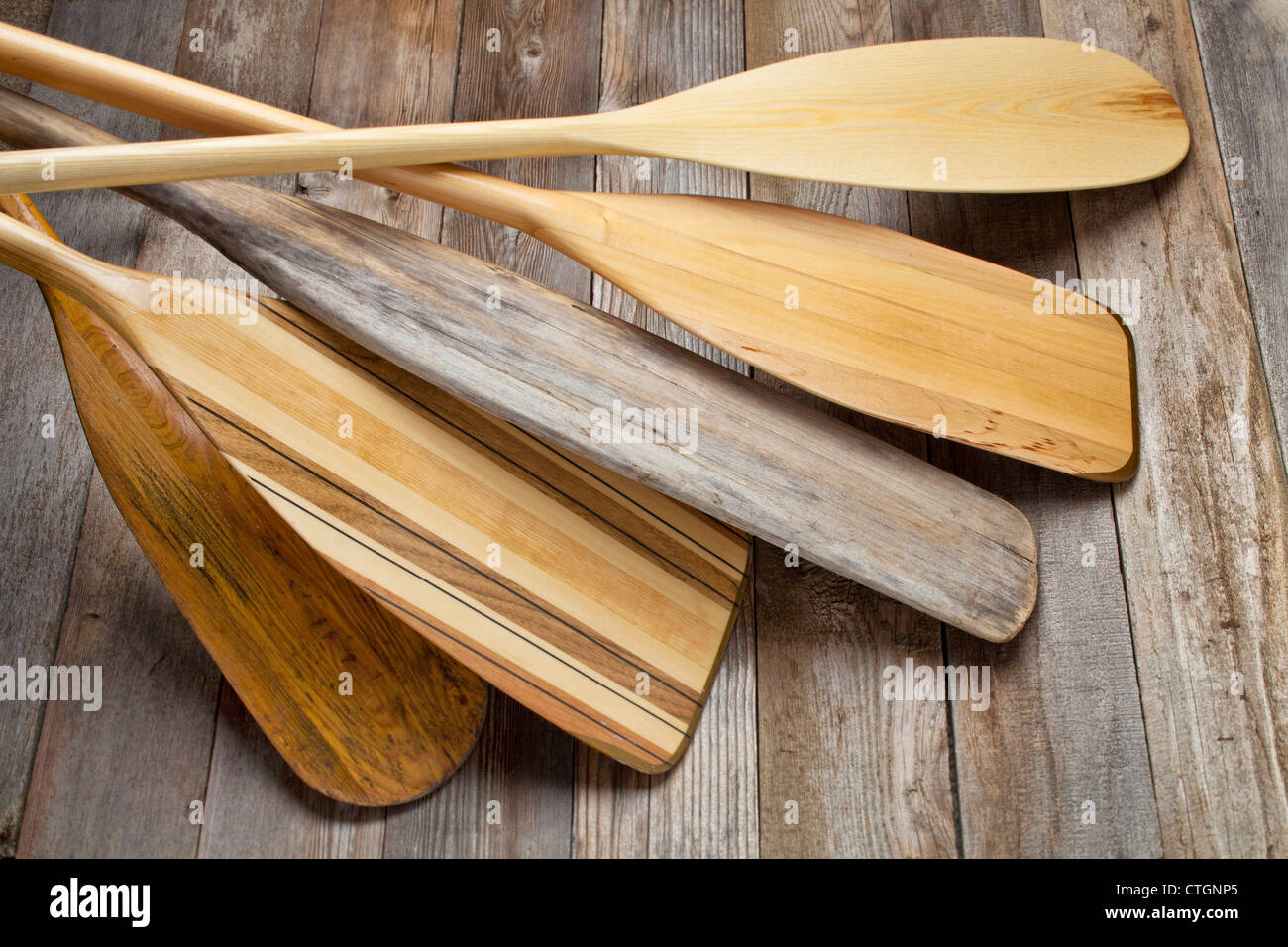 pile of wooden canoe paddles with different shapes and sizes of blades