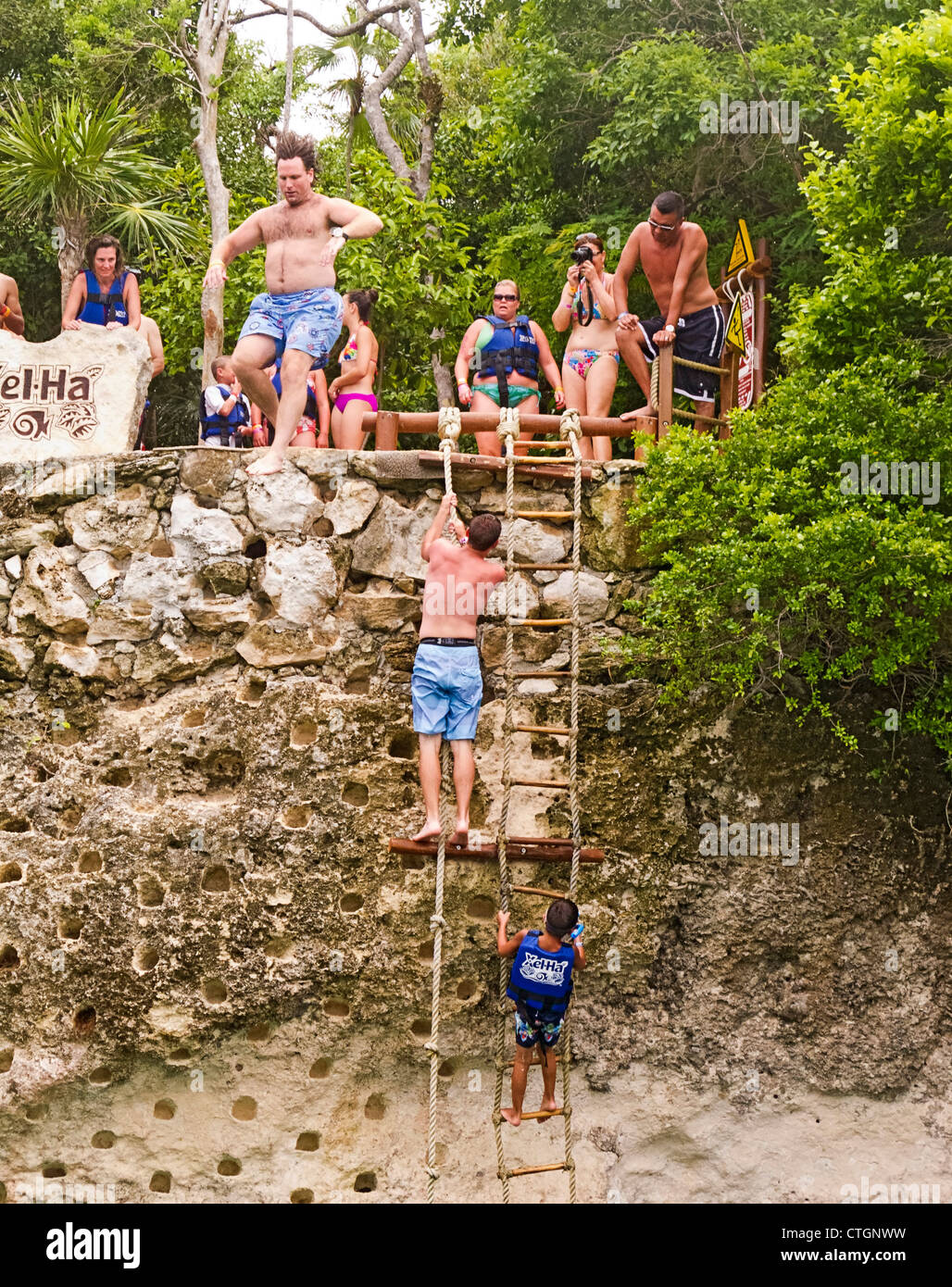 Children and adults jump from a cliff at Xel Ha, a water oriented, Disney like amusement park in