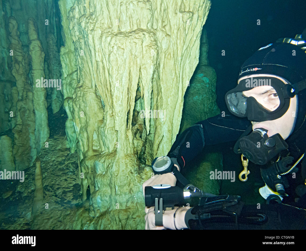 Scuba diver near one of the rock column formations in Dream Gate, one of the many cenotes where people can scuba dive in Akumal, Stock Photo