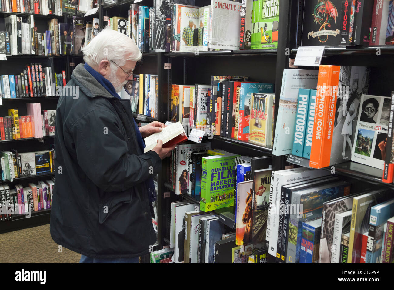 Cork, County Cork, Ireland. Elderly man reading book in Waterstone's book store. Stock Photo