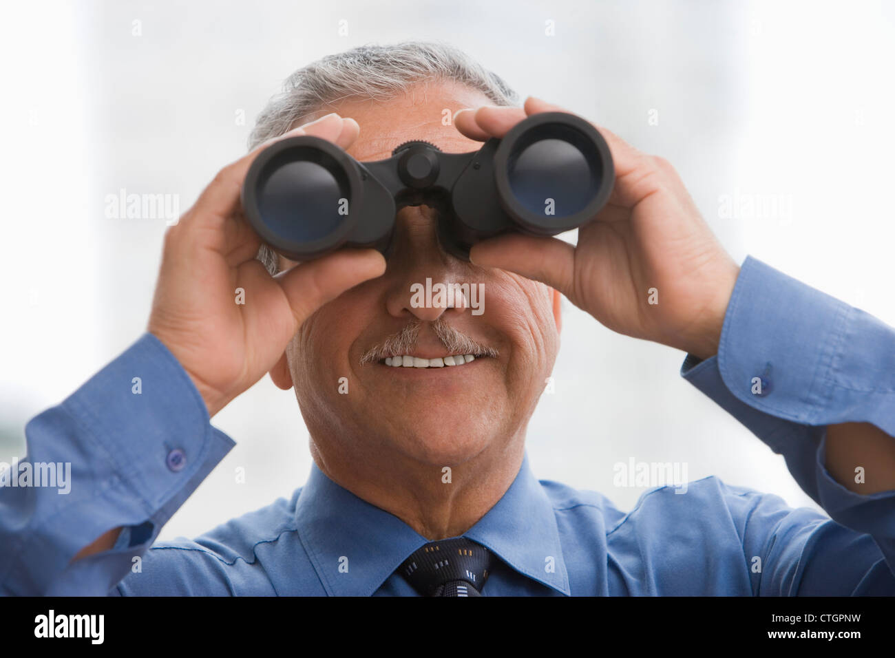 Hispanic businessman using binoculars Stock Photo