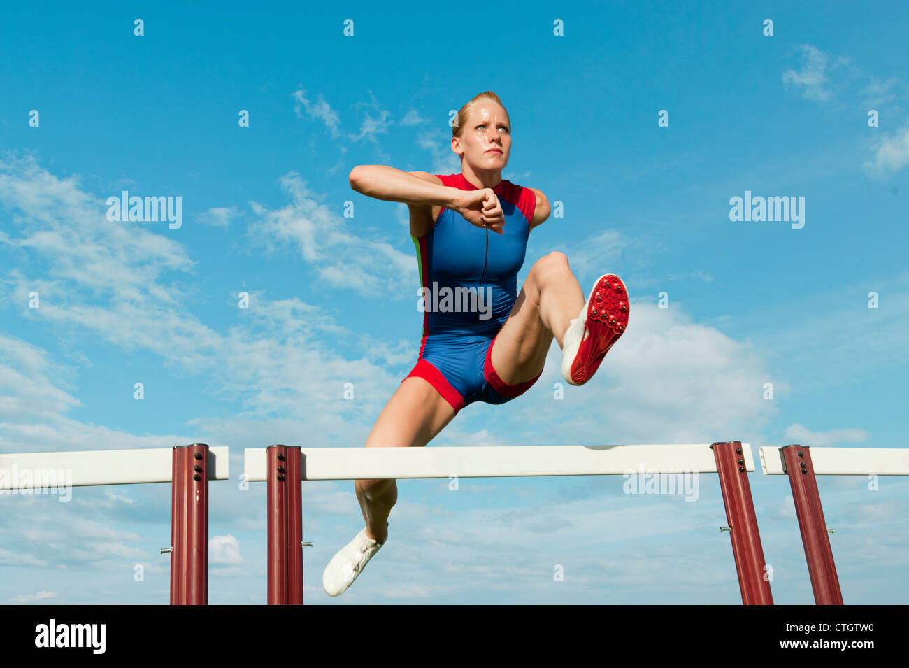 Caucasian runner jumping over hurdles on track Stock Photo Alamy