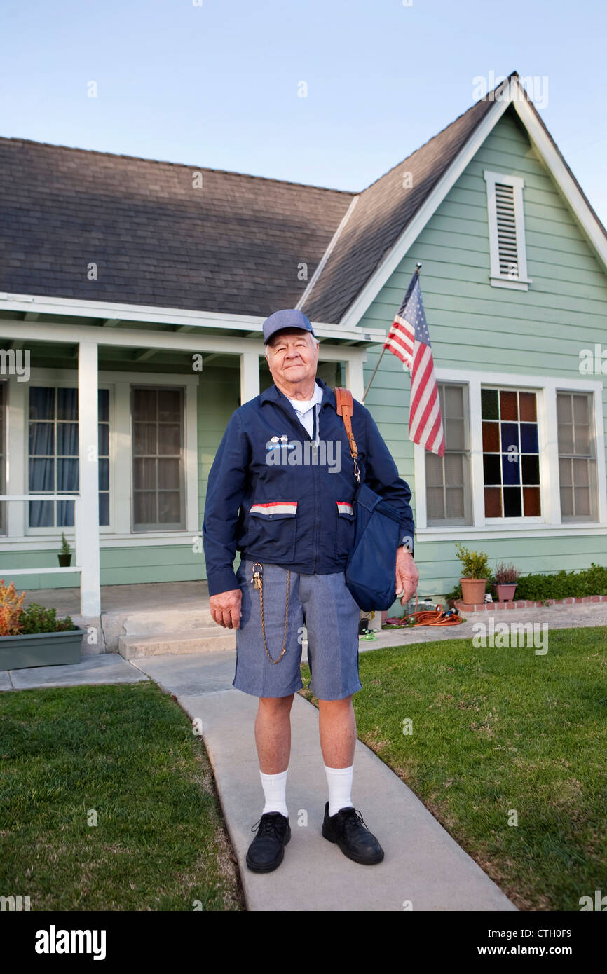 Caucasian mailman standing in front yard Stock Photo