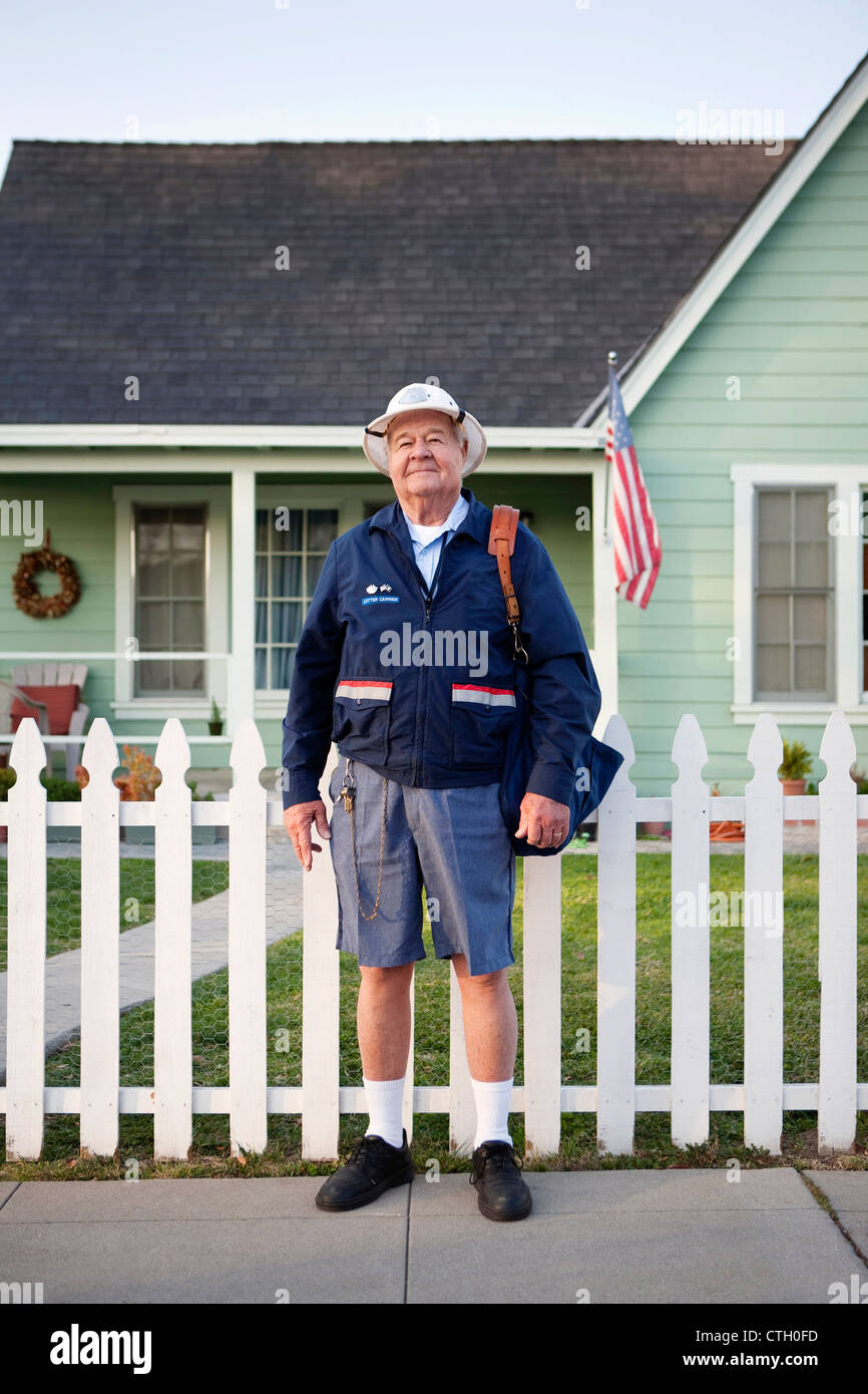 Caucasian mailman standing on sidewalk Stock Photo