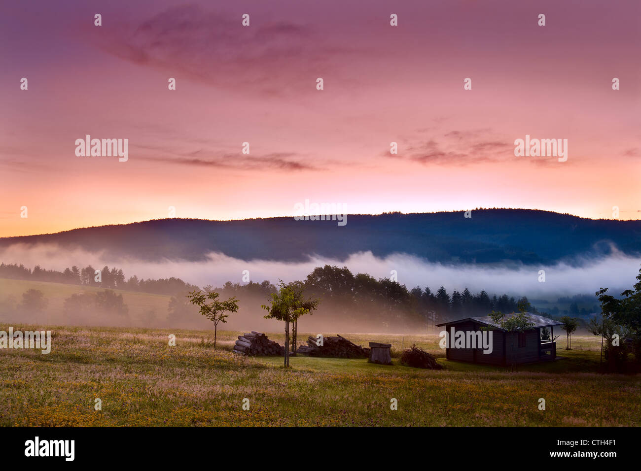 colorful sunrise on alpine meadows with wooden farm house Stock Photo