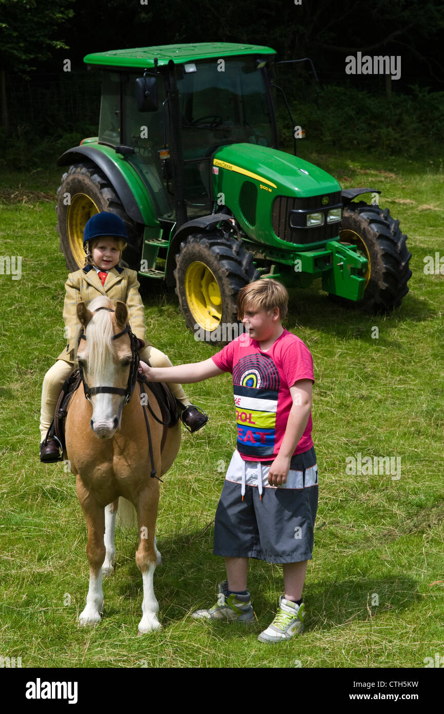 Young girl on pony with teenage boy handler at small rural country show on farm at Cwmdu Powys Wales UK Stock Photo