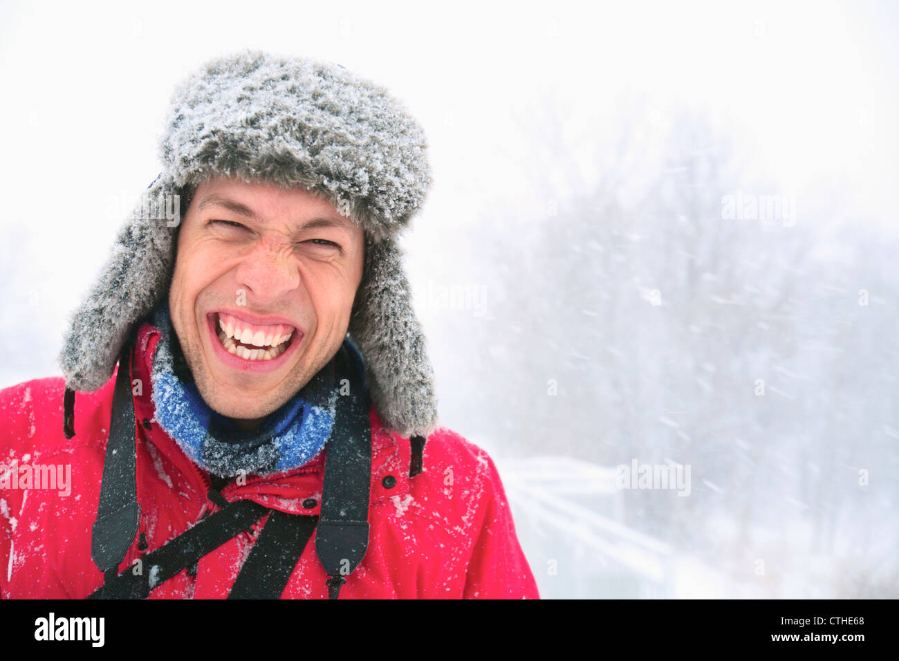 A Young Man Laughing A He Wears A Fur Hat Covered In Snow On A Snowy Day; Eagan, Minnesota, United States of America Stock Photo