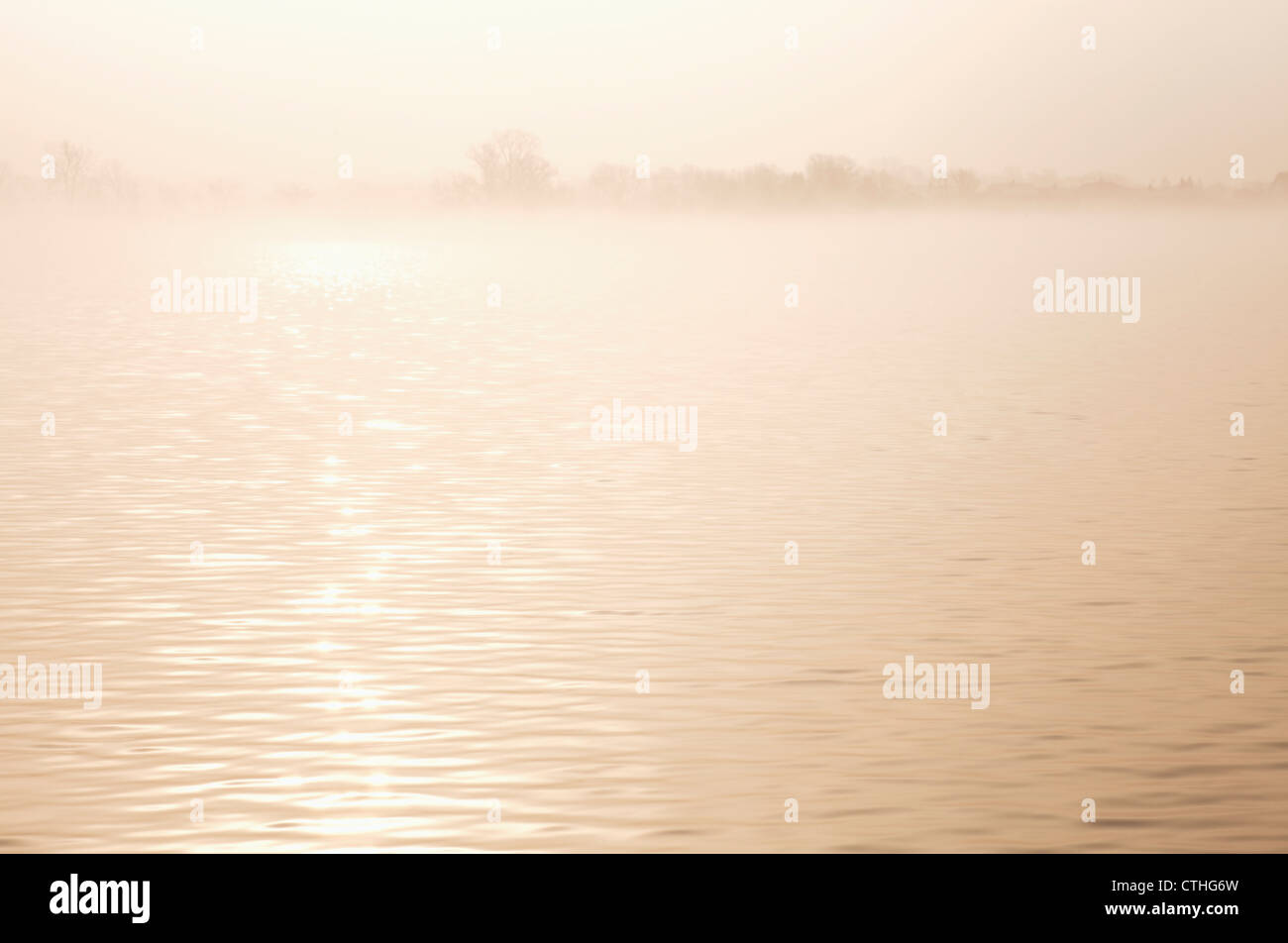 Sunlight Reflecting On The Water At Sunrise Through The Mist; Spicer, Minnesota, United States of America Stock Photo
