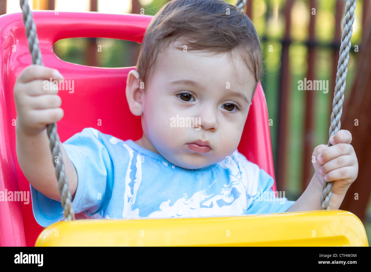 close-up of 9-month old baby boy in a swing outdoors Stock Photo