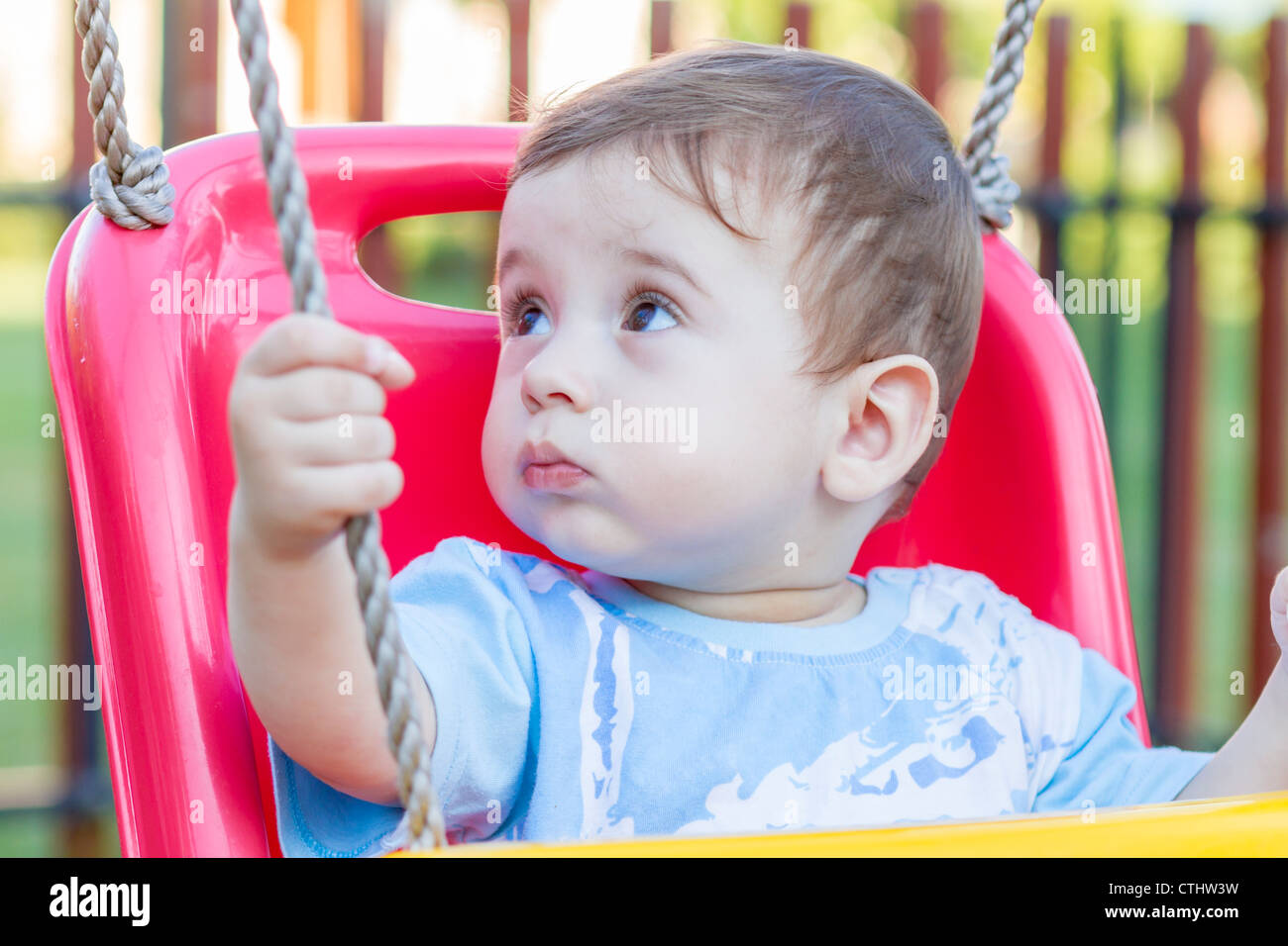 close-up of 9-month old baby boy in a swing outdoors Stock Photo