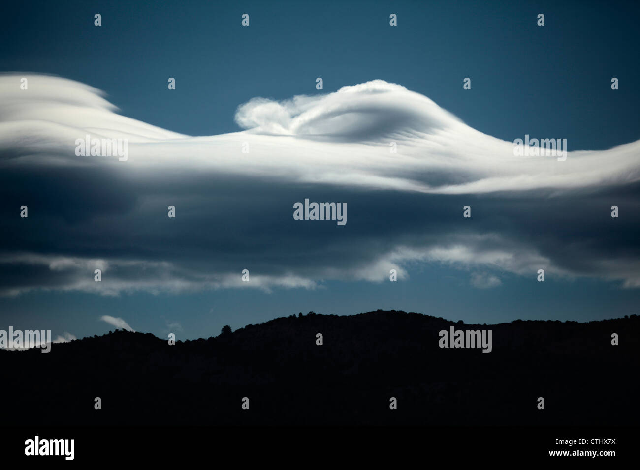 Lenticular cloud formation with a distinctive crashing wave top over Colorado's Rocky Mountains. Stock Photo