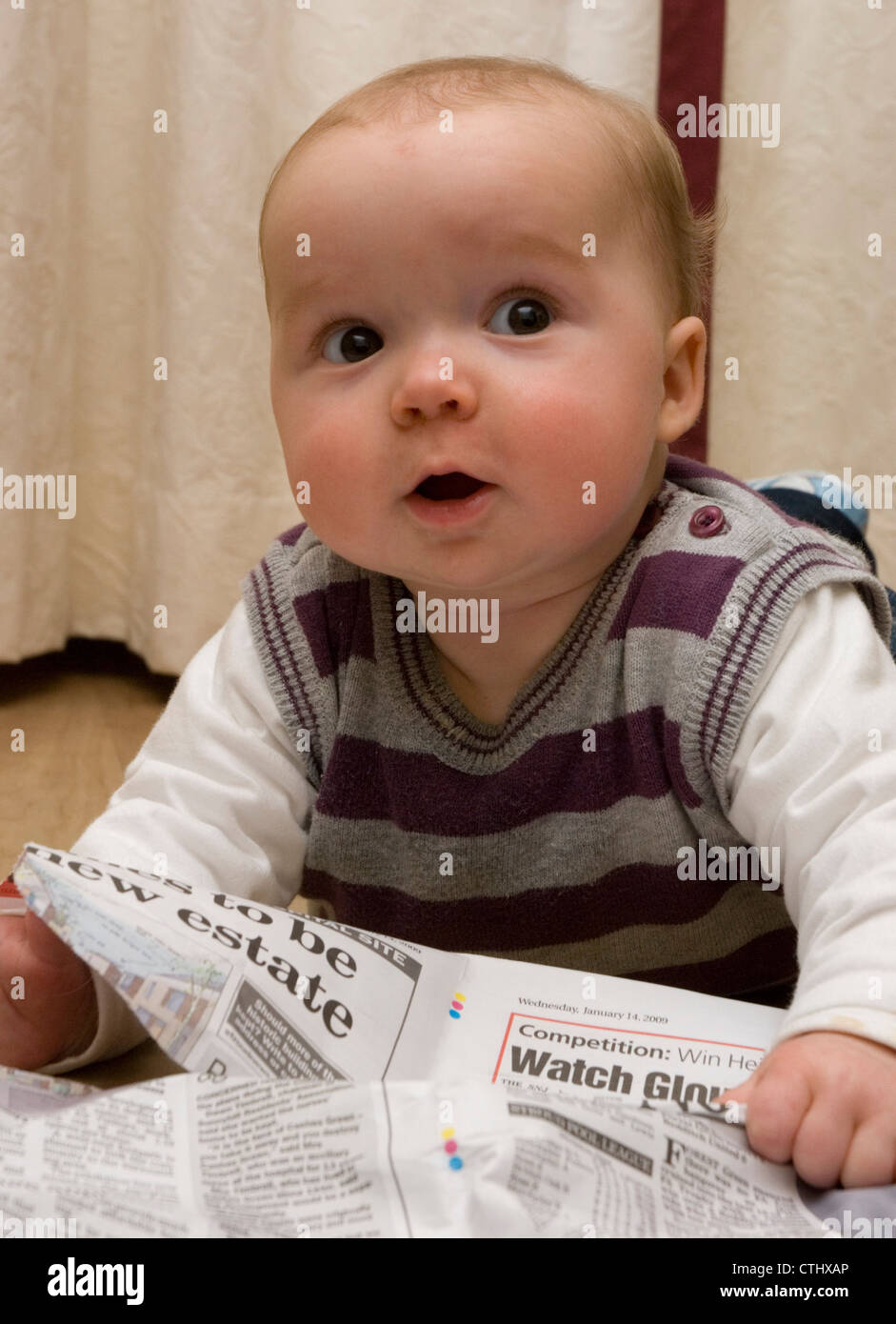 Baby 'reading' newspaper Stock Photo Alamy