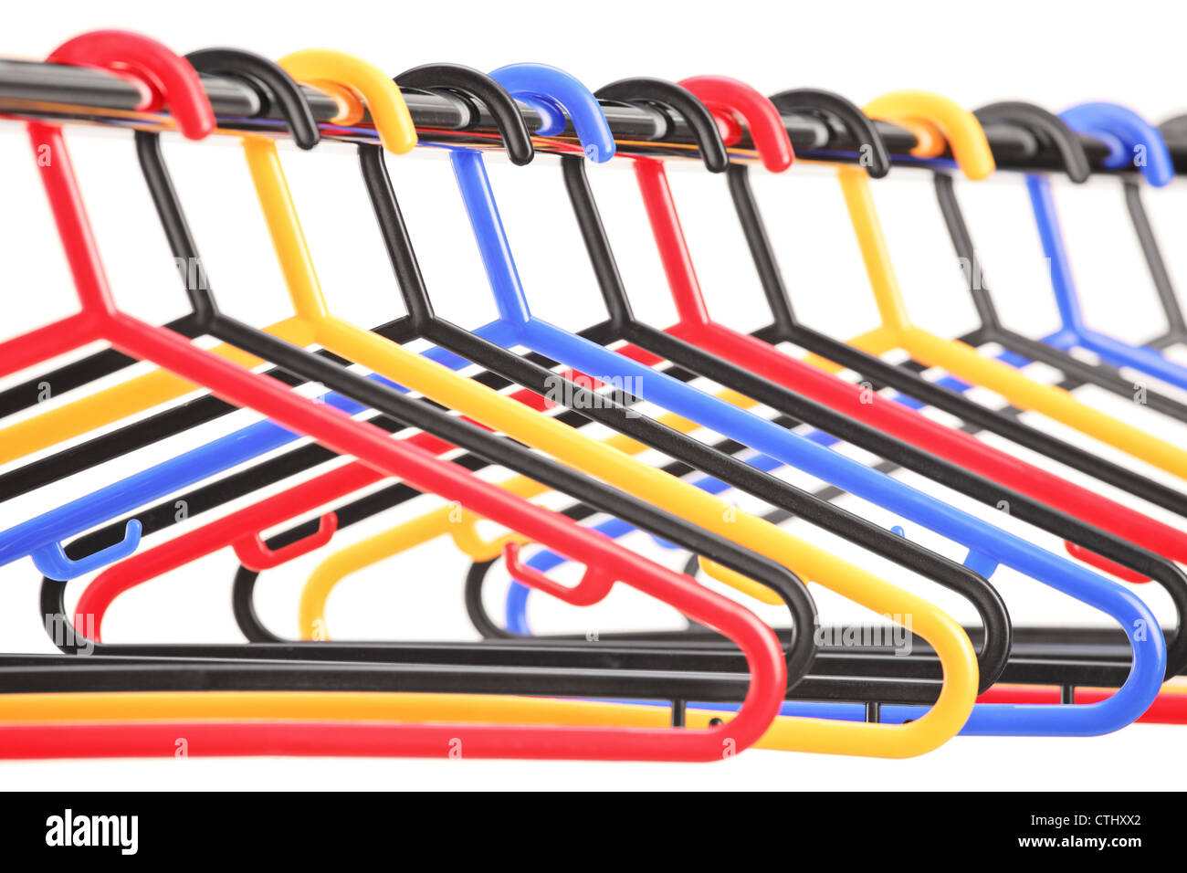 Empty plastic hangers on a rail with the focus on the fourth hanger, isolated on white background Stock Photo