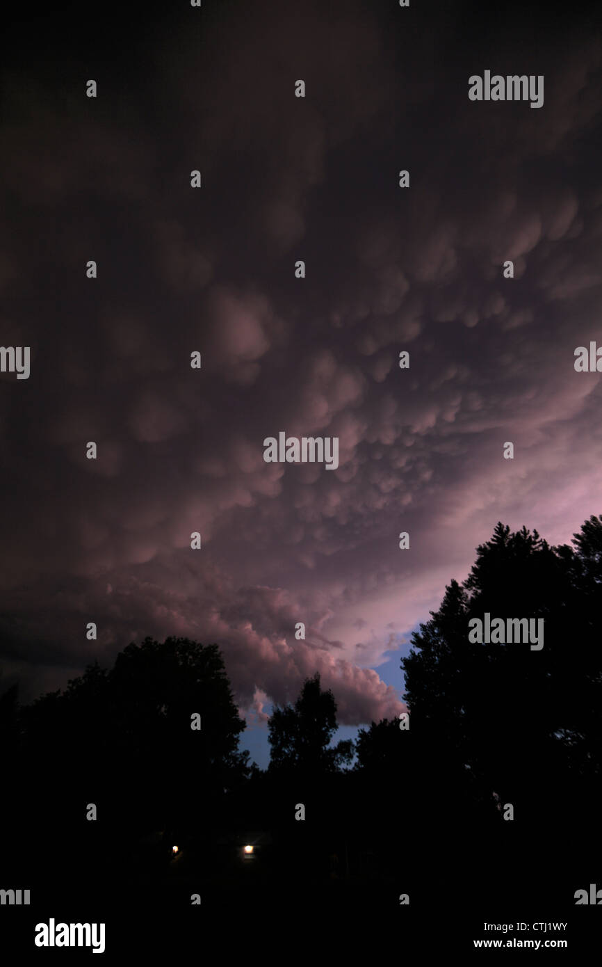 Trailing edge of a severe thunderstorm at sunset, showing deep purple coloration in a field of mammatus clouds. Stock Photo