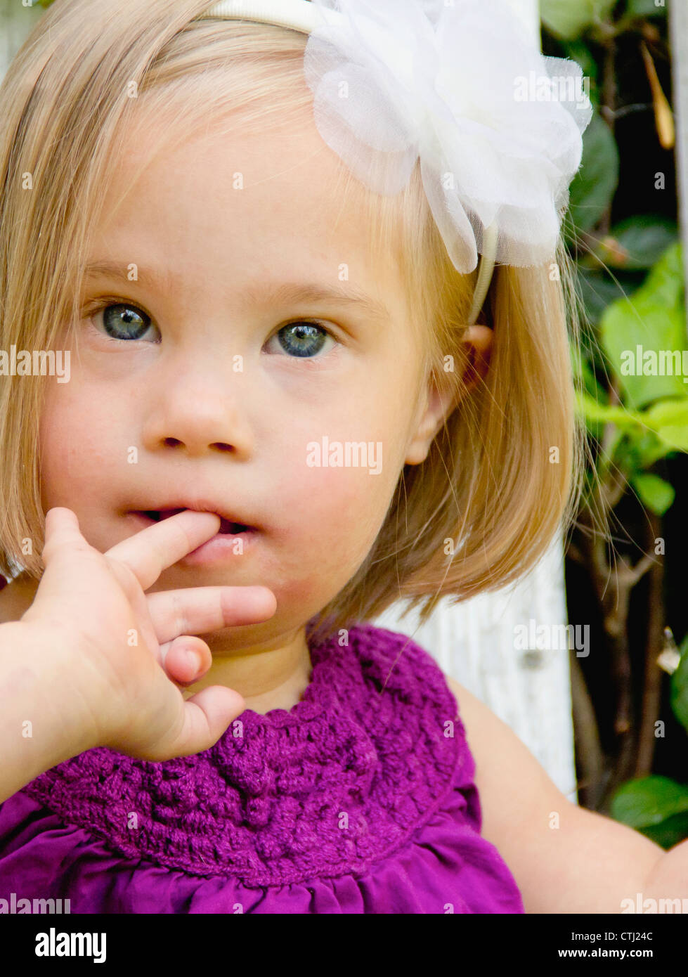 Portrait Of A Young Girl With Down Syndrome With Her Finger In Her Mouth; Three Hills, Alberta, Canada Stock Photo