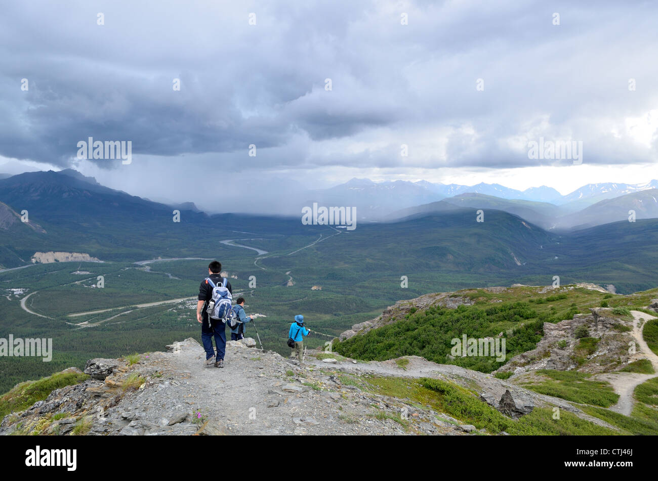 Family hiking on Mt. Healy trail under stormy clouds. Denali National