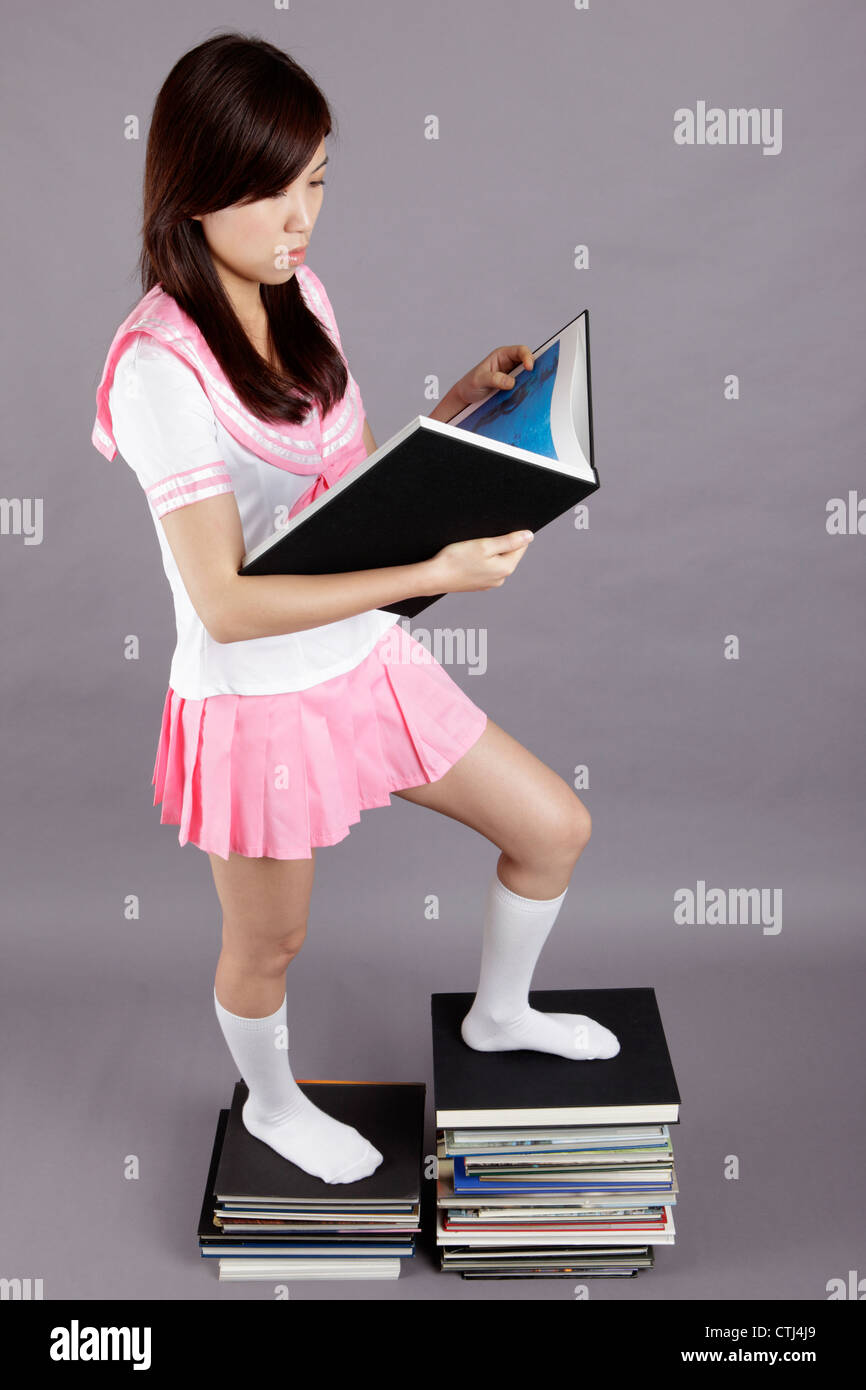 School girl stands on books Stock Photo - Alamy