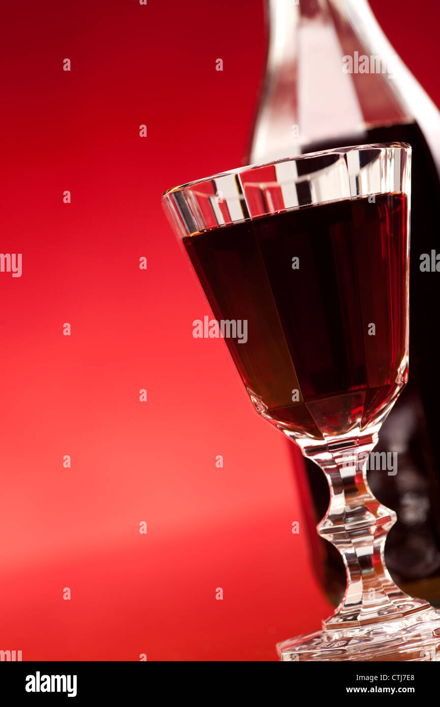 glass of red wine or liqueur on red background Stock Photo