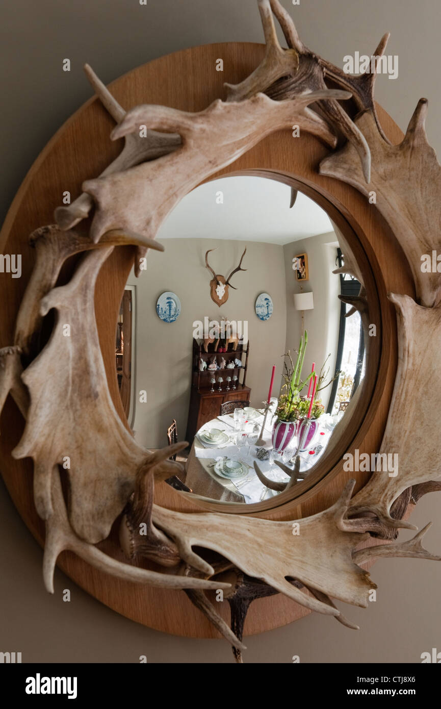 Reflection of a laid dining table seen in a round antler mirror made by