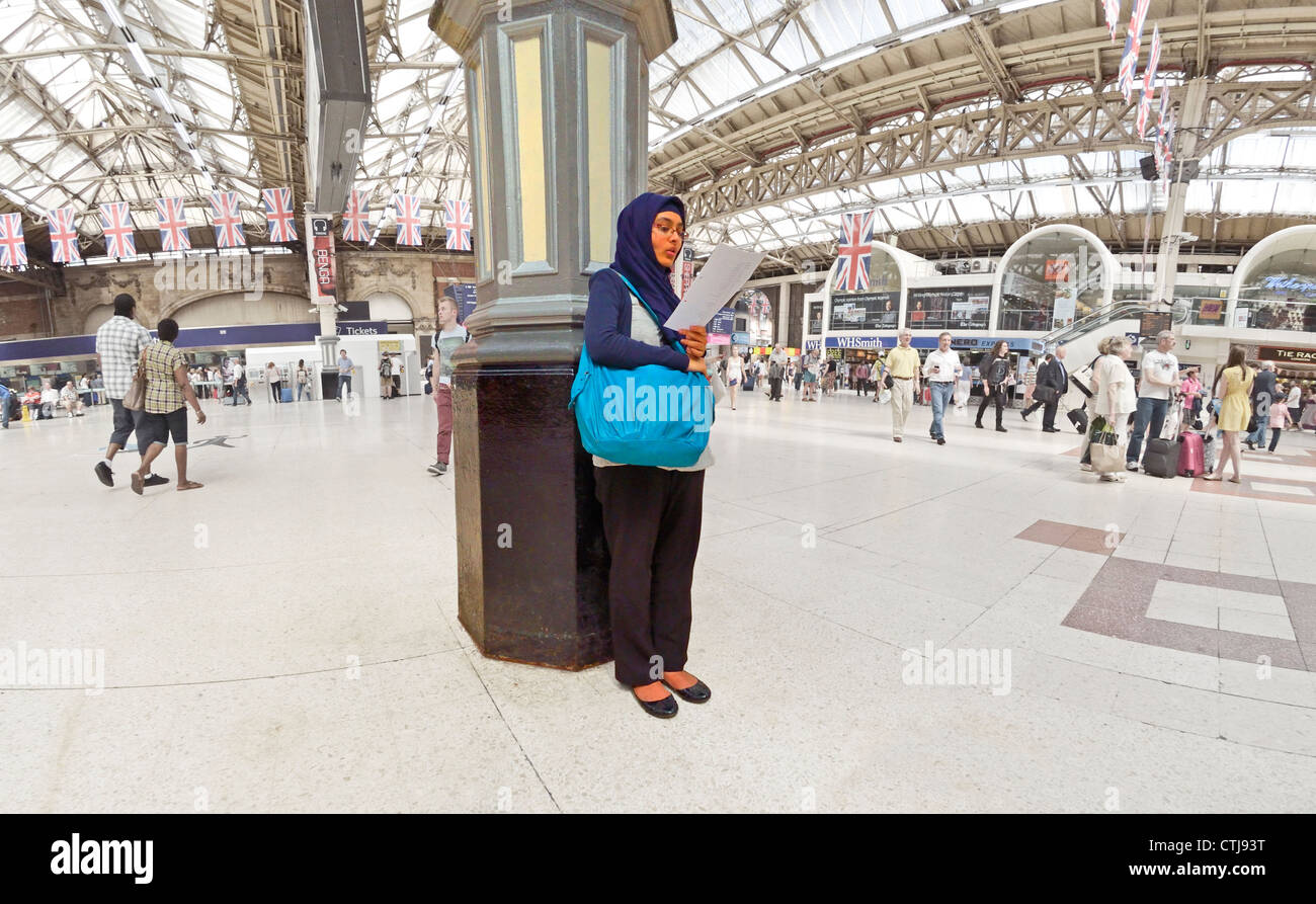 London, England, UK. Victoria Station. Muslim woman reading Stock Photo