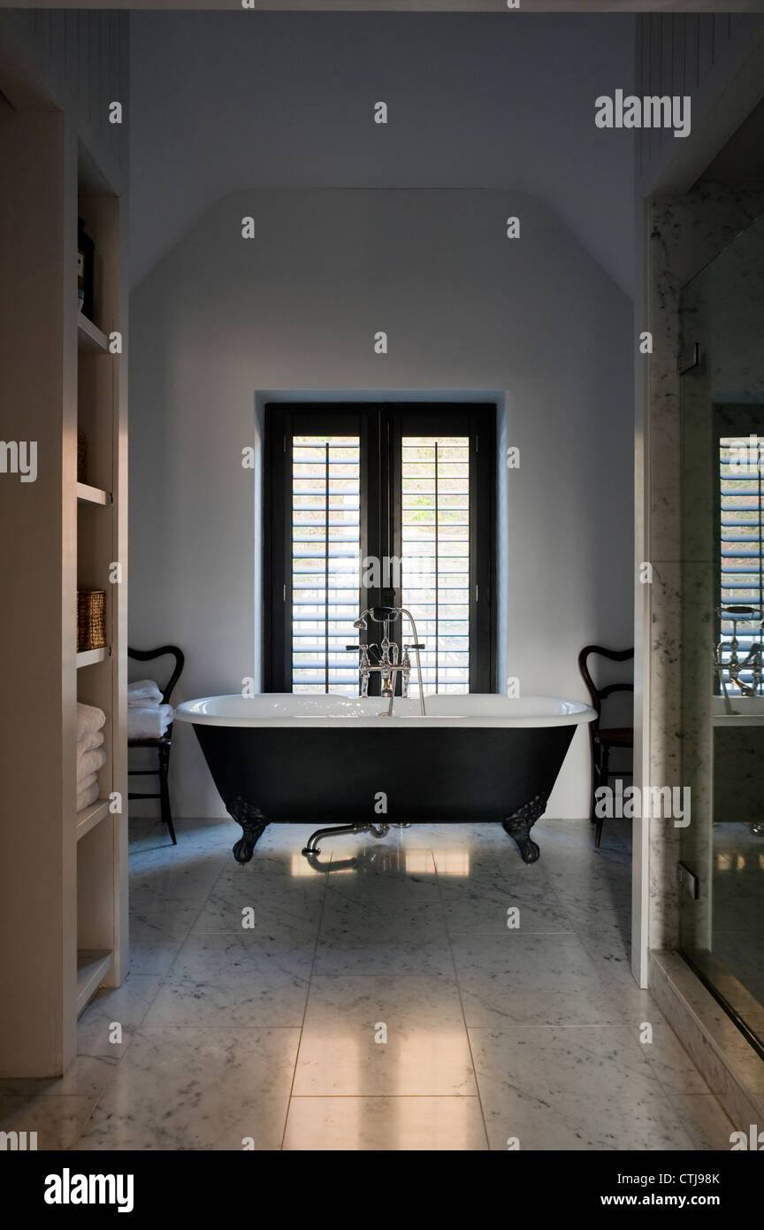 Freestanding double ended bath (similar The Spey from Drummonds) in bathroom with white marble floor tiles Stock Photo