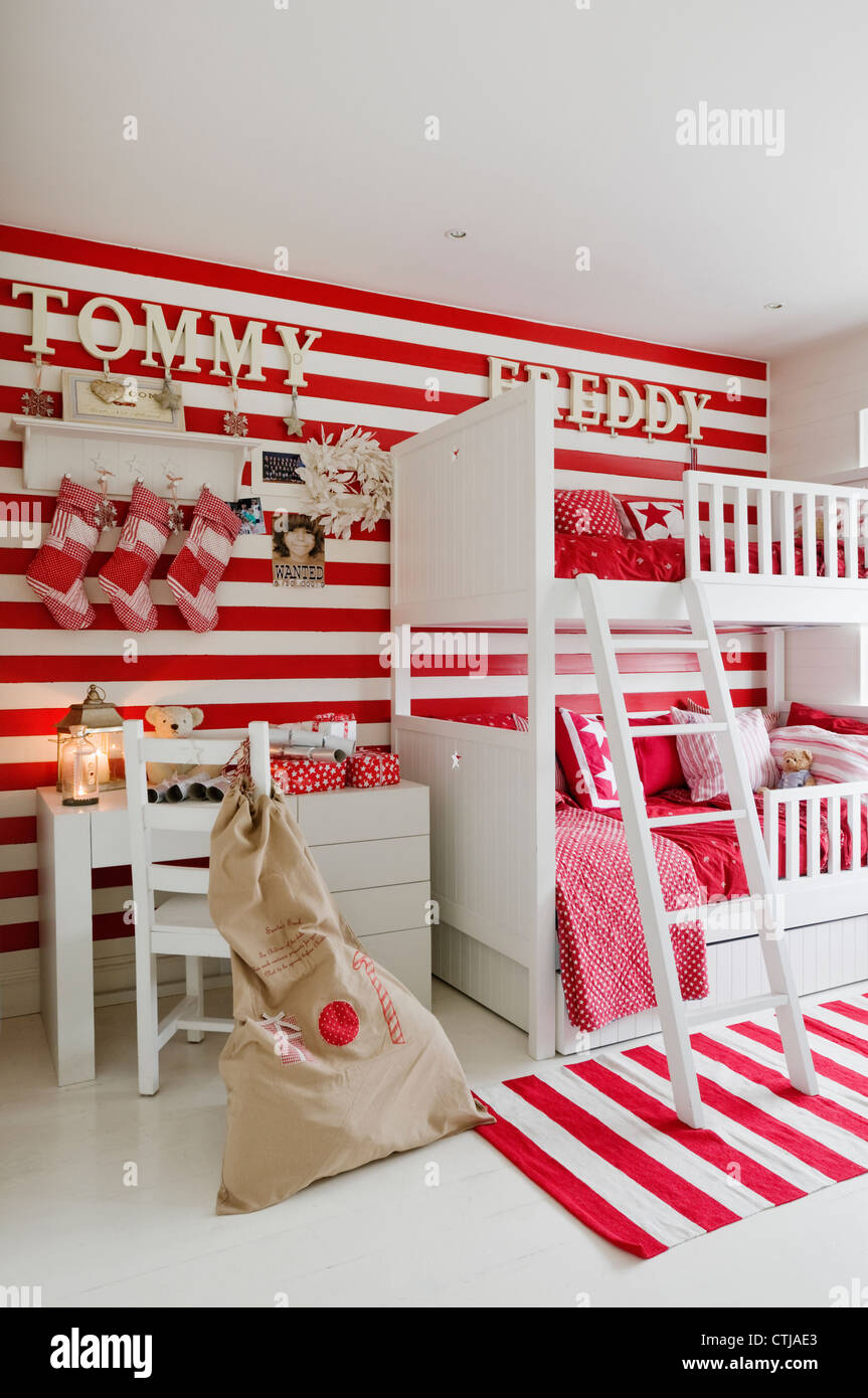Striped red and white wallpaper in children's room with patchwork Christmas stockings Stock Photo