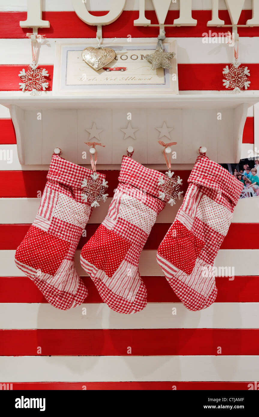 Striped red and white wallpaper in children's room with patchwork Christmas stockings Stock Photo