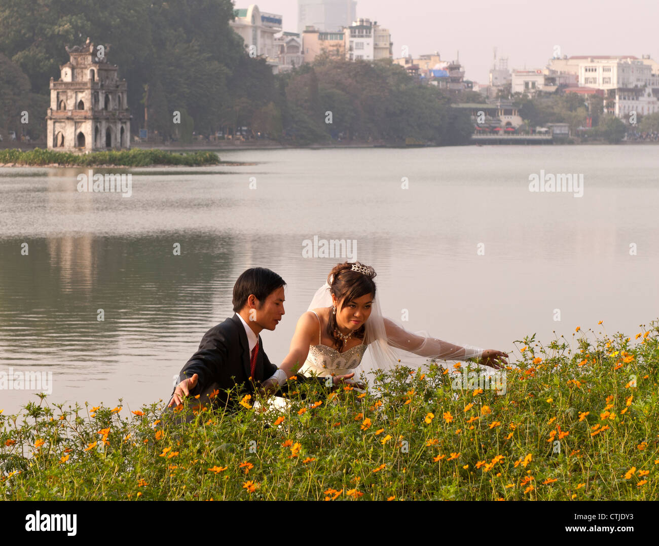 https://c8.alamy.com/comp/CTJDY3/vietnamese-wedding-couple-posing-with-the-torttoise-tower-in-the-background-CTJDY3.jpg