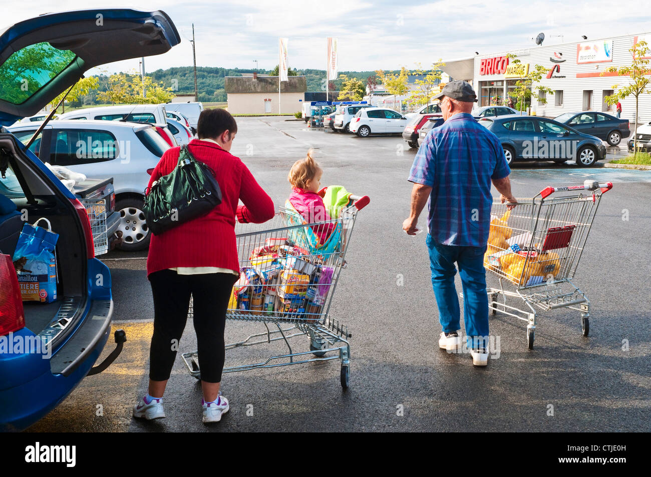 Shoppers unloading groceries in supermarket carpark France Stock