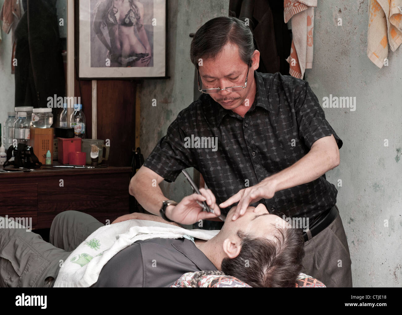 Traditional male barber hairdresser shaving customer in Hoi An, Viet Nam Stock Photo