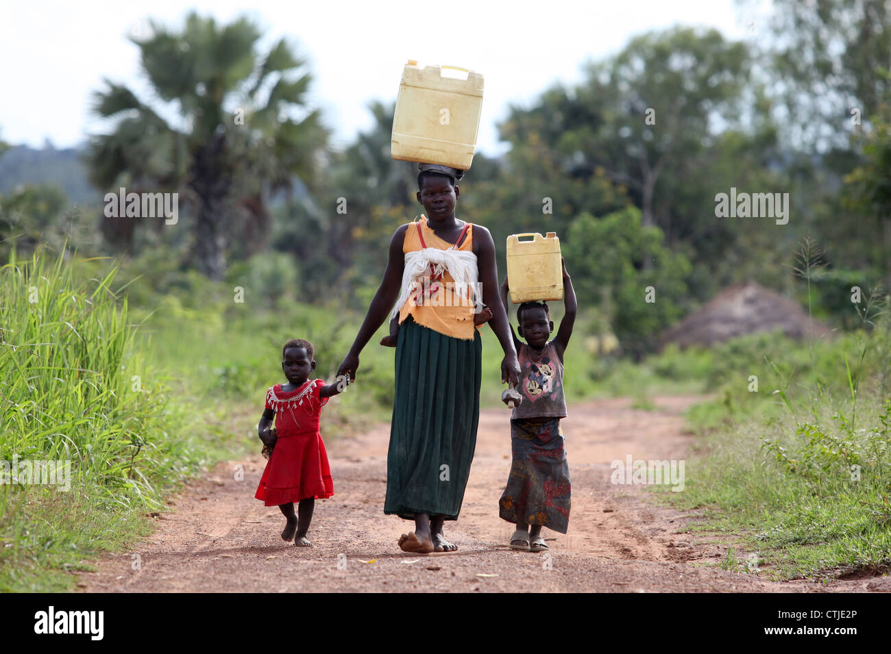 A mother and her children finish their day off by collecting dirty water in the Lira district of northern Uganda Stock Photo
