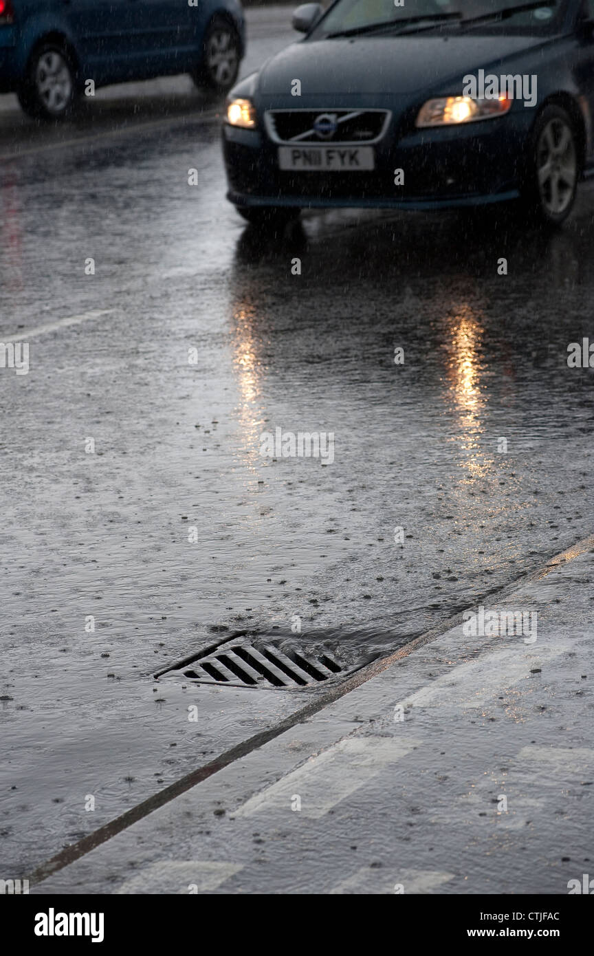 Water pouring down a drain at the side of a road during a storm in